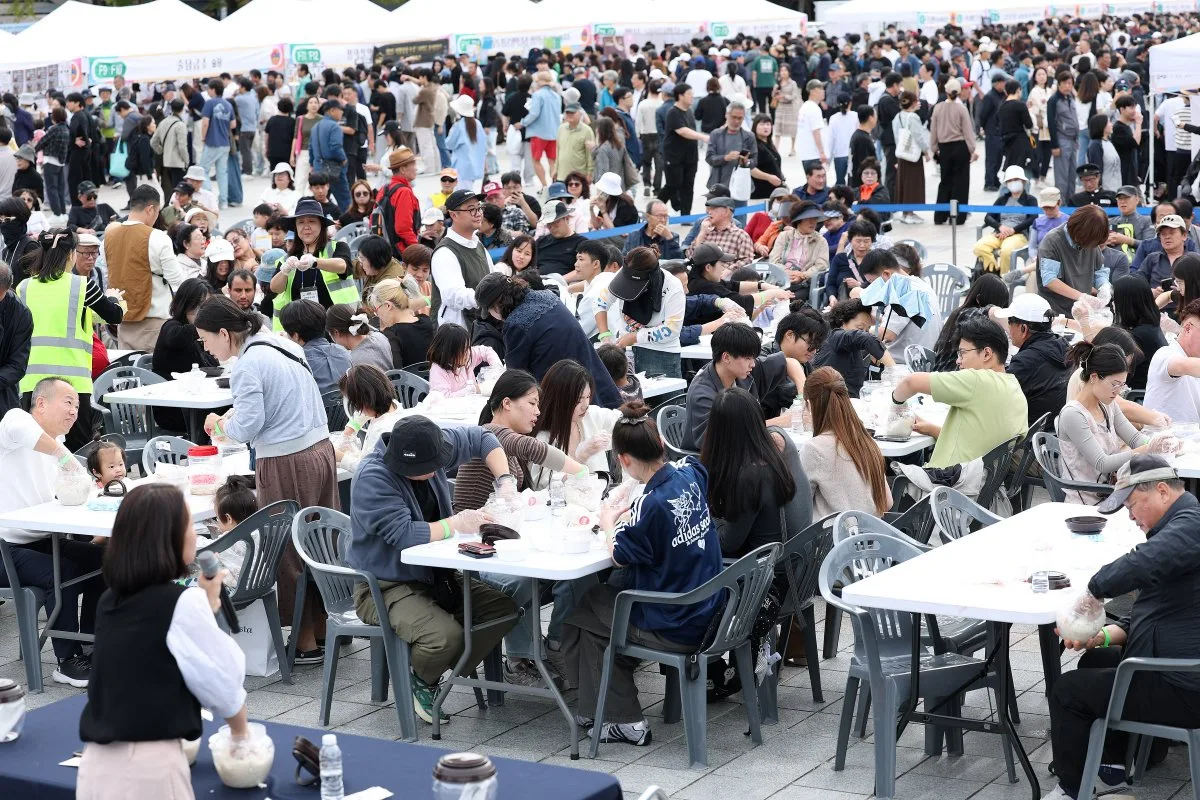 야외 부스에 많은 시민들이 둘러앉아 막걸리를 시음하고 대화하는 광경