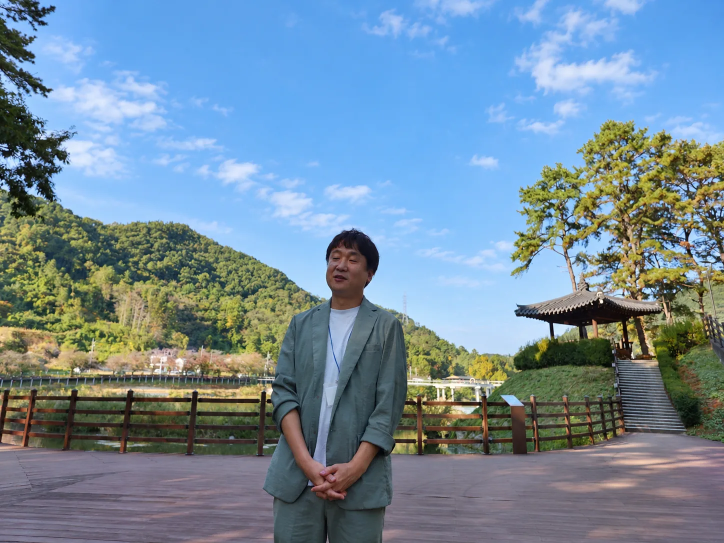산과 하늘, 전통 누각을 배경으로 한 남성 회원이 시 낭송을 하는 장면.
