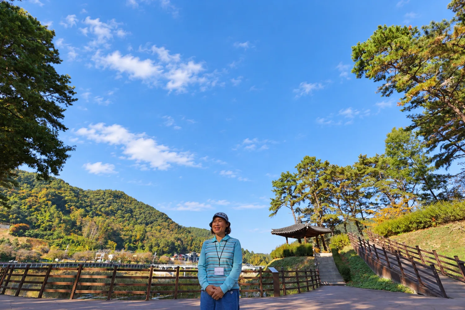 푸른 가을 하늘과 푸른 산을 배경으로 시를 낭송하는 여성 회원의 전신 모습.