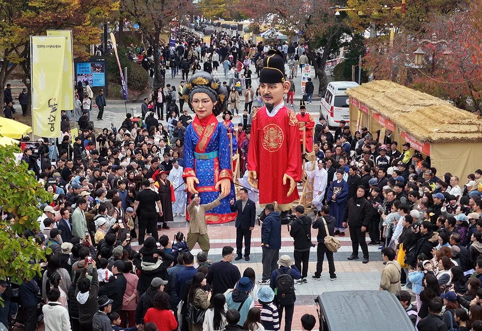 가을 축제장에 수많은 사람들이 긴 줄을 서서 부스 앞에서 대기하는 모습의 전경 사진