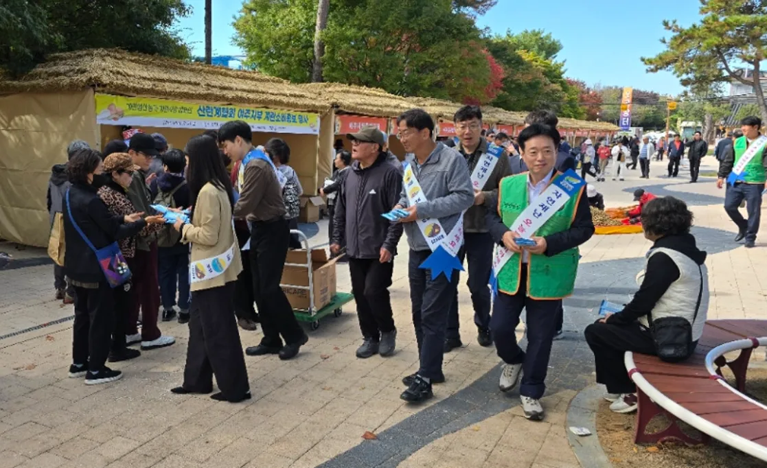 어깨띠를 두른 사람들이 축제장 거리에서 시민들에게 리플렛을 나눠 주며 캠페인하는 모습