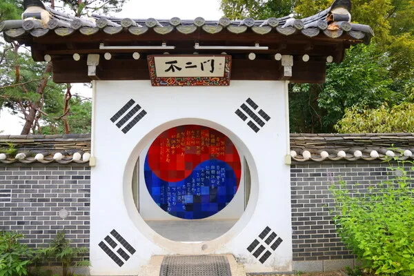 한옥 스타일의 문에서 보이는 태극 문양과 네 개의 괘 문양이 있는 원형 입구.