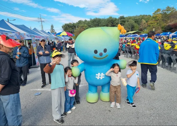야외 무대에서 공연 중인 가수들과 무대를 바라보는 관객들, 배경으로 붉은 단풍이 보인다.
