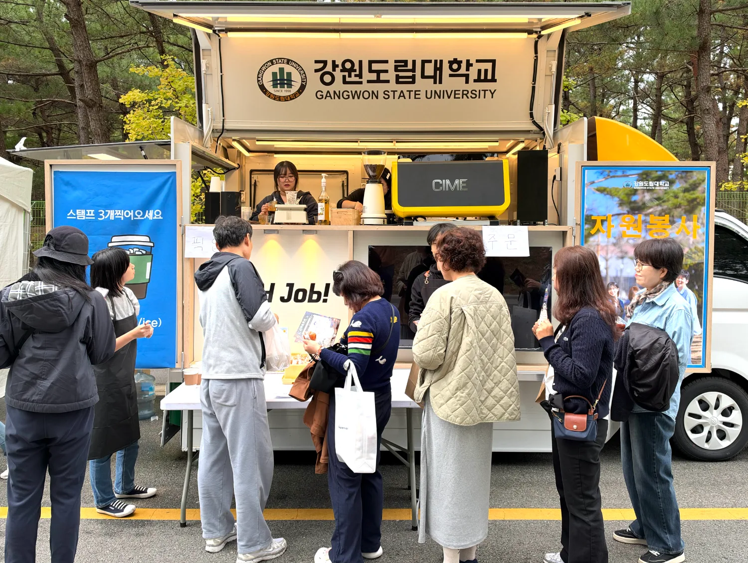 바닷가에 설치된 부스 앞에 어린이와 가족들이 줄 서서 체험을 기다리는 장면