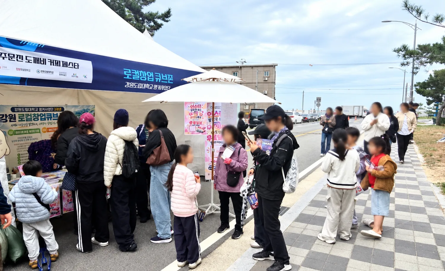 강원도립대학교 로고가 보이는 커피트럭 앞에서 사람들이 줄 서서 커피를 받고 있는 장면