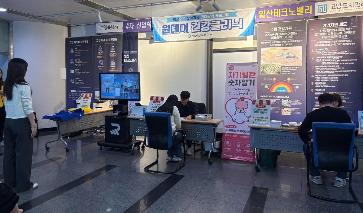 보건소 내 공간에서 책상에 앉은 한 남성이 컴퓨터 모니터를 보며 상담을 받고 있고, 상담사가 서서 지켜보고 있다.
