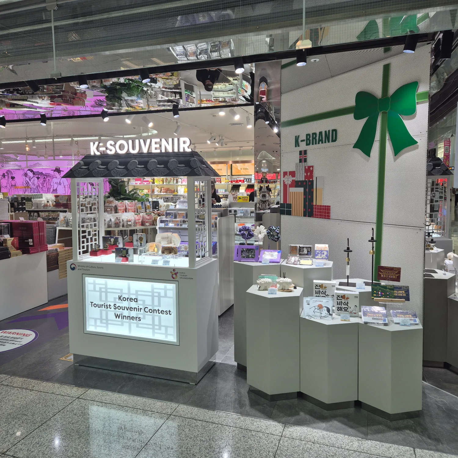 판판면세점 내부에 설치된 K-SOUVENIR 팝업 매장으로, 각종 한국 관광기념품들이 진열된 진열대와 간판이 보인다.